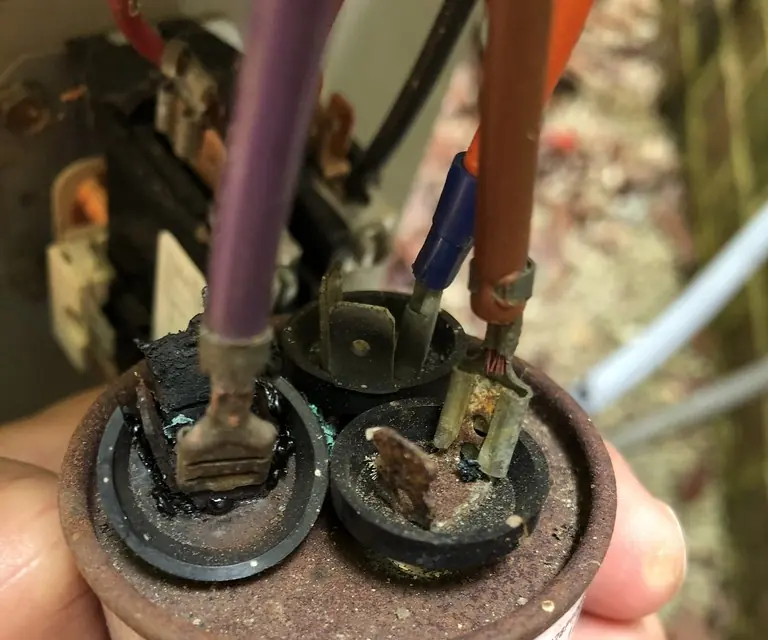 Burned and corroded terminals on a failed air conditioner run capacitor